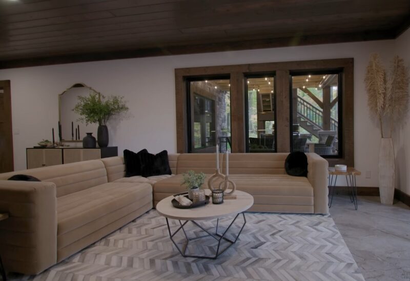  A cabin lounge area featuring a plush beige sofa, geometric-patterned rug, black and gold decor