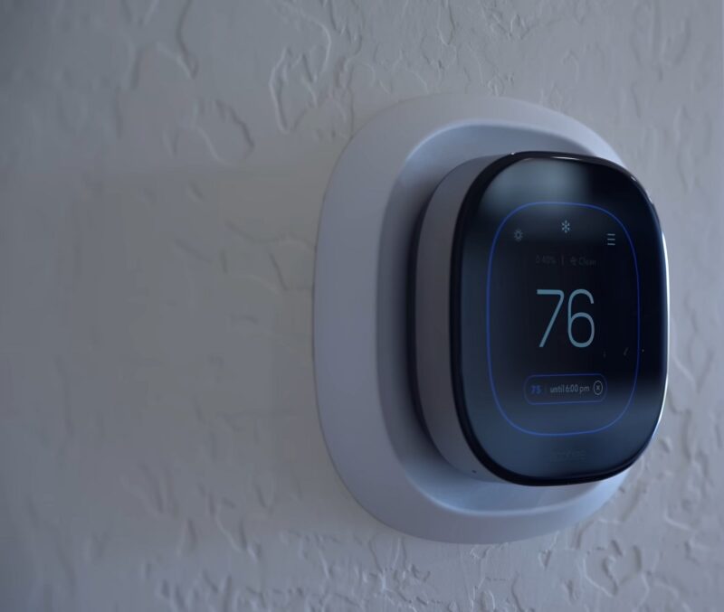 A smart thermostat mounted on a textured wall