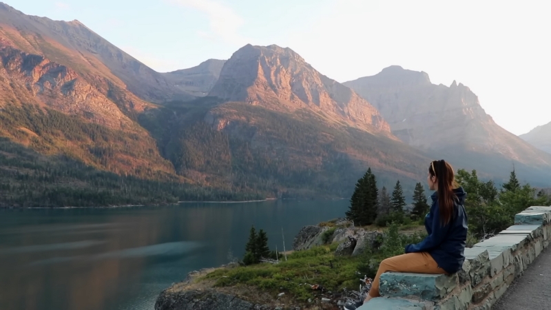 A Person Sitting by A Lake, Enjoying the Scenic View of The Mountains in Glacier National Park